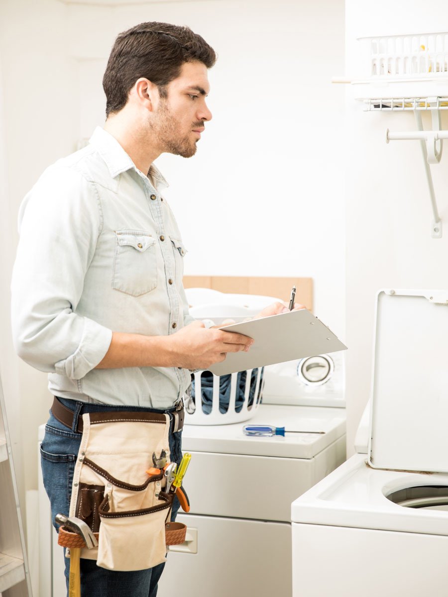 young male electrician doing some repairs laundry room looking washing machine (2)